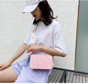 Detailed close-up of pink daisy print crossbody bag with wide floral textile strap
