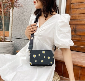 Detail of black crossbody bag with daisy prints and adjustable wide floral shoulder strap