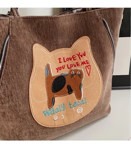 Close-up of brown corduroy tote bag featuring a cute cat plush patch and embroidery