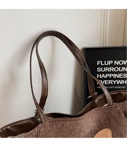 Detail of brown corduroy tote bag featuring smooth PU leather straps and retro texture