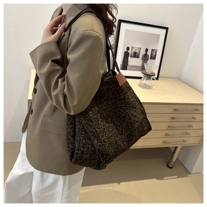 Detail of leopard print tote bag with outer pocket and rivet detail worn by a model