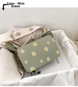 Detail view of mint green crossbody bag with daisy prints and a wide floral shoulder strap