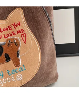 Detail of brown corduroy bag with cat patch embroidery and metallic zipper close-up