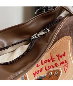 Detailed close-up of smooth metal zipper head and embroidered cat design on the tote bag