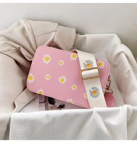Detail of pink crossbody bag with white daisy prints and adjustable wide strap