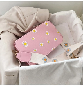 Detail of pink floral crossbody bag with white daisy prints and wide canvas shoulder strap