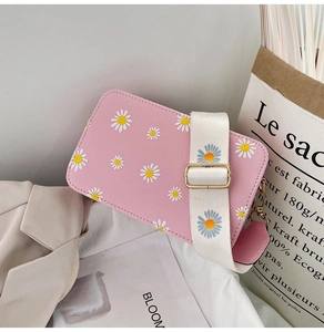 Detail of pink floral crossbody bag featuring white daisy prints and wide shoulder strap