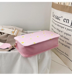 Close-up of pink daisy floral shoulder bag with wide strap and golden metal clasp