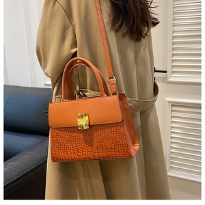 Sac à main marron à texture crocodile porté à l'épaule dans un intérieur moderne