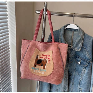 Detail view of pink corduroy tote bag with cat embroidery and zipper accents on a rack