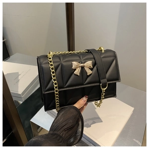 Détail du sac matelassé noir avec fermoir nœud doré et bandoulière en chaîne métal