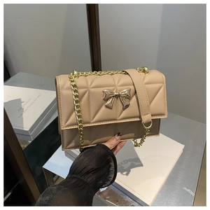 Détail du sac à bandoulière matelassé abricot avec fermoir nœud doré et chaîne en métal
