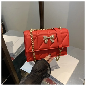 Détail du sac rouge matelassé avec fermoir nœud doré et bandoulière en chaîne