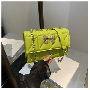 Détail du sac bandoulière matelassé vert fluo avec fermoir papillon doré et chaîne