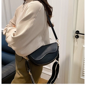 Détail du sac selle noir avec double bandoulière, bord ondulé et finitions dorées