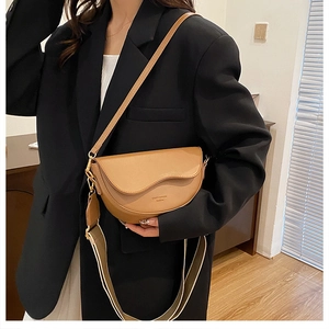 Sacoche selle marron en cuir avec double bandoulière sur un blazer noir élégant