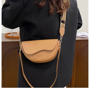 Détail d'un sac besace marron avec rabat ondulé et des ferrures dorées de haute qualité