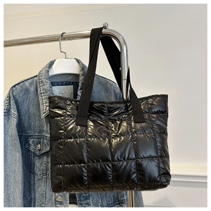 Détail du sac cabas matelassé noir brillant suspendu sur un support en métal moderne