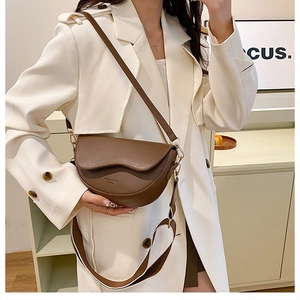 Détail du sac selle en cuir marron montrant le design demi-lune et la bandoulière