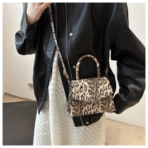 Fashionable leopard print handbag with silver hardware shown as a crossbody on a model