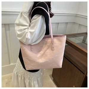 Detailed side view of pink tote bag with pleated texture and gold rivet hardware