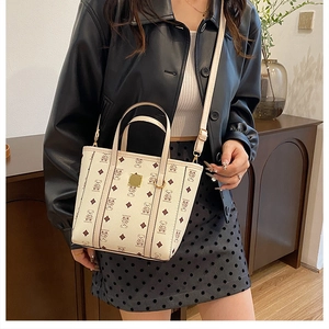 Détail d'un sac seau crème avec motif d'ours porté sur une veste en cuir noir
