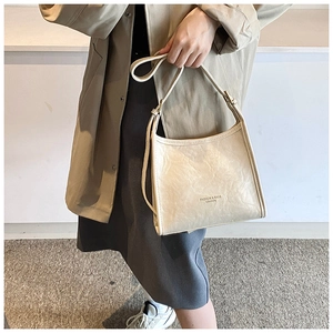 Detail of beige pleated leather shoulder bag with FASHION & BAGS text and fine stitching