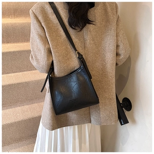 Detail of black pleated shoulder bag with gold metal buckle and leather texture