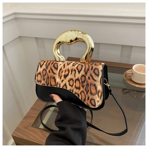 Detail of leopard print flap and modern gold-shaped handle on stylish crossbody handbag