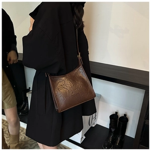 Detail view of dark brown leather shoulder bag with vintage texture and embossed lettering