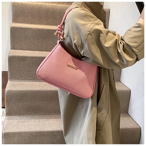 Detail view of pink textured fabric shoulder bag with knot strap and gold metal accent
