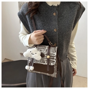 Close-up of a vintage brown checkered crossbody bag with plush cloud charm and gold buckle