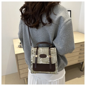 Detail of retro vintage crossbody bag with abstract texture and leather trim on wooden shelf