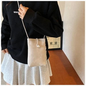 Détail du mini sac bandoulière crème avec fermoir perle et breloque à franges longues