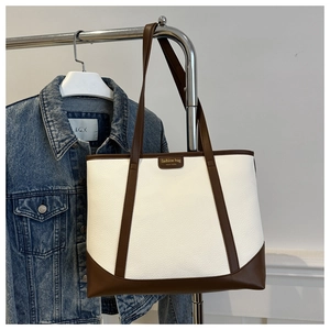 Detail of minimalist tote bag showing white lychee texture and brown contrast stitching