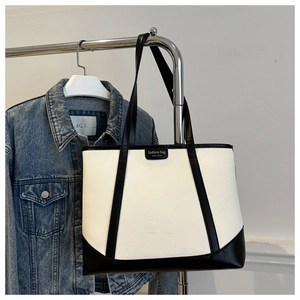Detail of lychee textured tote bag with contrast piping and fashion brand label