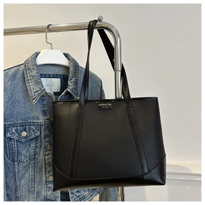 Detail of black faux leather tote bag with gold fashion bag New York logo branding
