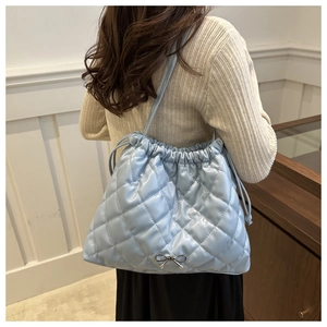 Quilted light blue drawstring tote bag with silver bow detail shown on shoulder