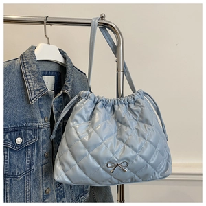 Detail of light blue quilted tote bag featuring drawstring and silver bow accent