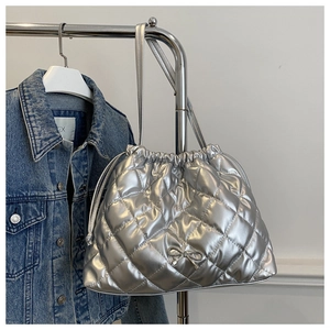 Close-up of a silver quilted tote bag with a bow accent hanging on a hanger