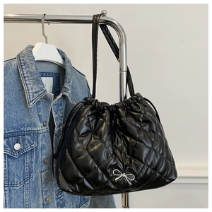 Detail of quilted black tote bag featuring a silver bow and drawstring closure