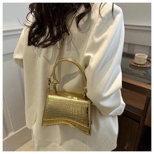 Detail of gold crocodile embossed hourglass handbag with thick top handle and strap