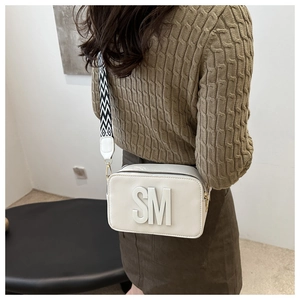 Détail du sac bandoulière blanc avec logo SM et large bandoulière à motifs zigzag