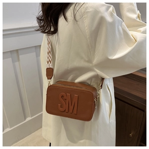 Gros plan d'un sac caméra marron en similicuir avec lettres gaufrées et sangle