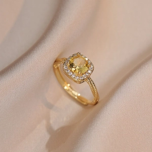 Bague dorée élégante avec zircon jaune carré et anneau perlé sur soie champagne