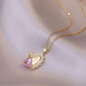 Pink heart zircon necklace with gold chain and micro-paved crystals on satin background