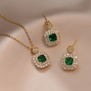 Emerald green zircon pendant necklace and earrings set in gold finish on champagne satin