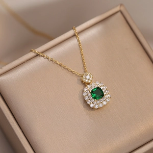 Detailed view of emerald green square pendant with double halo stones on a golden chain