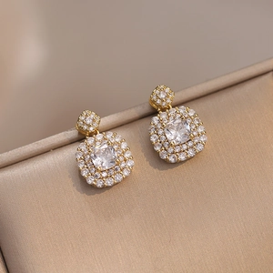 Macro shot of gold square emerald-cut zircon stud earrings with double halo detail