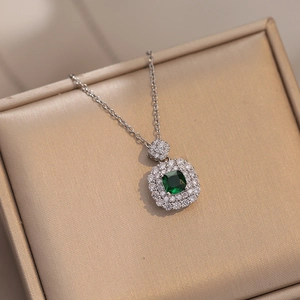 Detailed macro shot of an emerald green zircon halo pendant necklace on champagne silk